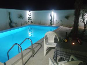 House with pool - Mitrovic في هرسك نوفي: مسبح في الليل مع طاولة وكراسي