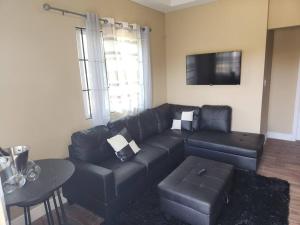 a living room with a black leather couch and a table at StoneSide Villa in Providenciales