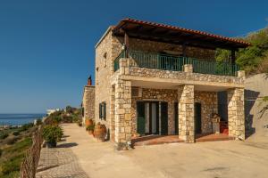 a stone house with a balcony on a hill at Agnadia Villa in Stalos