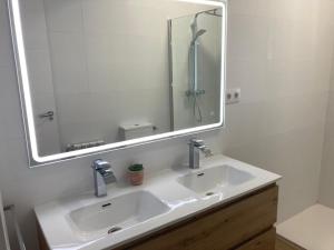 La salle de bains est pourvue d'un lavabo et d'un grand miroir. dans l'établissement Magnífico piso con gran terraza en centro de Vigo, à Vigo