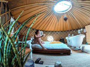 Una donna seduta su un letto in una yurta di Cerchio Del Desiderio Glamping Retreat a Pescara
