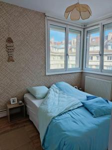 una camera da letto con letto con lenzuola e finestre blu di L'écume d'ancres a Calais