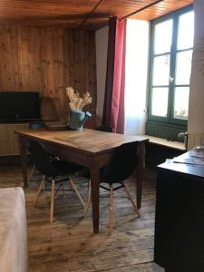 une table en bois dans un salon avec deux chaises dans l'établissement ancienne maison de tisserande atypique, à Mornac-sur-Seudre