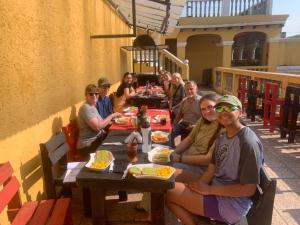 eine Gruppe von Menschen, die an einem Tisch mit Essen sitzen in der Unterkunft Ciudad Vieja Bed & Breakfast Hotel in Guatemala