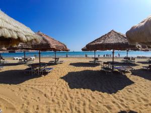 una spiaggia con ombrelloni e sedie di paglia e l'oceano di Novatek Apartment 202 Exclusive a Pescara
