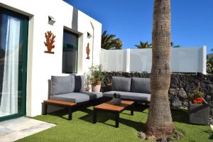 a patio with two couches and a palm tree at Bungalow La Palmera - 2 bedroom - PLAYA ROCA residence sea front access - Pool View - Free AC - Wifi in Costa Teguise