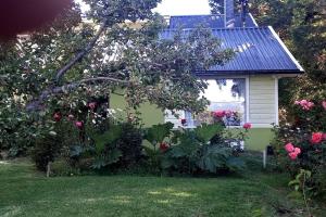 a small white house with a garden of roses at Cabaña Liebe Inge in San Carlos de Bariloche