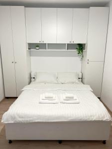 シビウにあるSiebenbürger Hausの白いキャビネット付きの客室の白いベッド1台