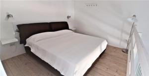 una camera da letto con un letto con lenzuola bianche e una lampada di Casa di Marco a Lecce
