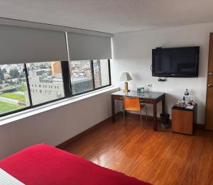 a bedroom with a desk and a television and a bed at Hotel Oceanía Bogotá Museo in Bogotá