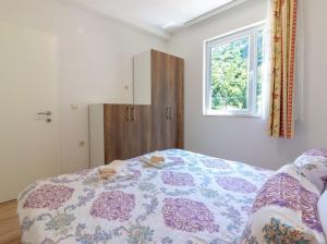 a bedroom with a bed with a flowered blanket and a window at VILA NAUM in Ohrid