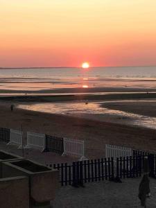 a sunset on a beach with the sun setting over the ocean at kerwatt in Cabourg