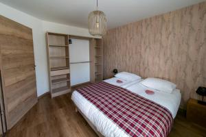 ein Schlafzimmer mit einem Bett mit einer rot-weißen Decke in der Unterkunft Gite Junior L'Ecrin du Ried PROCHE EUROPA-PARK in Artolsheim