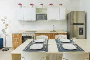 una cocina con una mesa con platos y sillas blancos en Lovely Space 4 Blocks From The Beach en Playa del Carmen