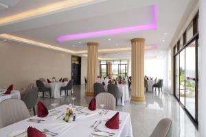 a restaurant with white tables and chairs and columns at Las Vegas Garden Hotel Mbarara in Mbarara