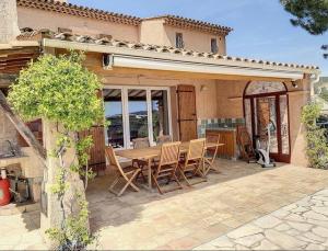 un patio con mesa de madera y sillas frente a una casa en Villa sainte maxime golfe de Saint Tropez, en Sainte-Maxime