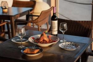 Sunset Sea View في Elíka: طاولة مع أطباق من الطعام وزجاجة من النبيذ