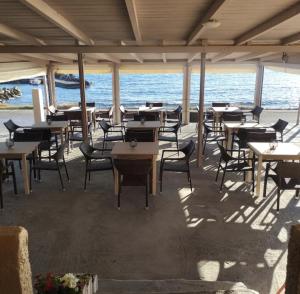a restaurant with tables and chairs and the ocean at Sunset Sea View in Elíka