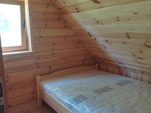 Cette cabane en rondins comprend un lit dans une chambre avec fenêtre. dans l'établissement Za Potokiem, à Grywałd