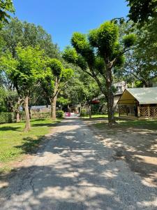 un chemin de terre avec des arbres et un kiosque dans l'établissement Camping Beaussement Samouraï, à Chauzon