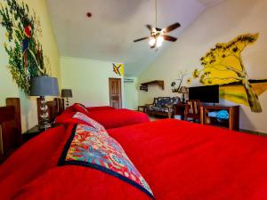 1 dormitorio con cama roja y sofá en Las Lajas Beach Resort, en Las Lajas
