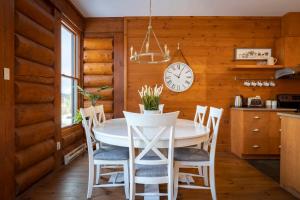 a dining room with a table and chairs and a clock at REFUGE 132 - 3 chambres + Spa by Reserver.ca in Lac-Superieur