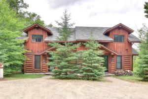 a large wooden house with a driveway in front of it at REFUGE 132 - 3 chambres + Spa by Reserver.ca in Lac-Superieur
