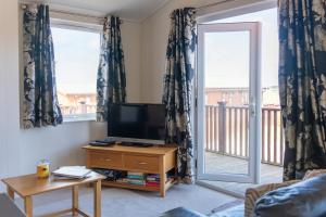 a living room with a flat screen tv and two windows at 56 Meadow View in Woolacombe