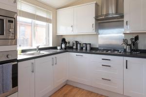 a white kitchen with white cabinets and a sink at 56 Meadow View in Woolacombe