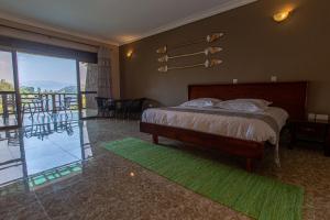 a bedroom with a bed and a view of a balcony at Bunyonyi Overland Resort in Kabale
