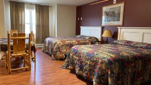 a hotel room with three beds and a table and chairs at Denali Rainbow Village RV Park and Motel in McKinley Park
