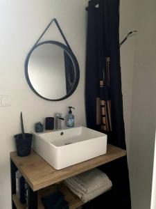 een badkamer met een witte wastafel en een spiegel bij Logement près des vignes in Crozes-Hermitage
