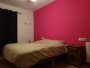 ein Schlafzimmer mit einer rosa Wand und einem Bett in der Unterkunft Mirador del Olivar in Olvera