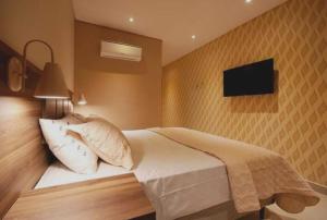 a bedroom with a bed and a tv on the wall at Guess Hotel & Motel in Guarulhos