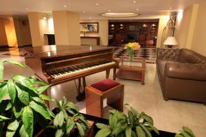 een woonkamer met een piano en een bank bij Hotel Windsor House Inn By GEH Suites in Bogota
