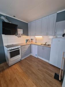 een keuken met witte kasten en een witte koelkast bij Storgalten gjestehus in Nord-Lenangen