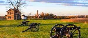 a group of cannons in a field with an old building at Holiday Inn Manassas - Battlefield, an IHG Hotel in Manassas