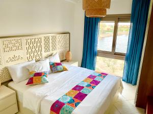 ein Schlafzimmer mit einem weißen Bett mit Kissen und einem Fenster in der Unterkunft The Penthouse in Marassi in El-Alamein