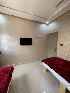 a room with two beds and a tv on the wall at hôtel Bahnini in Dakhla