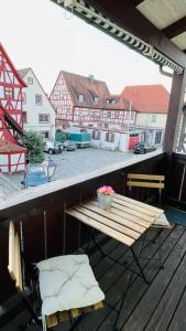 un balcone con tavolo e sedie in legno su un patio. di Mitten in den Weinbergen a Sommerhausen