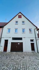 a white building with brown doors on a brick street at Mitten in den Weinbergen in Sommerhausen