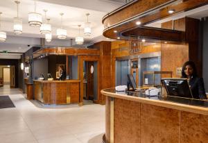 a woman standing at a counter in a lobby at Tavistock Hotel in London