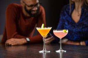 een man en een vrouw aan een tafel met twee cocktails bij Tavistock Hotel in Londen
