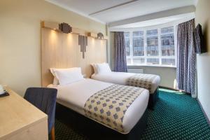 2 Betten in einem Zimmer mit Fenster in der Unterkunft Tavistock Hotel in London