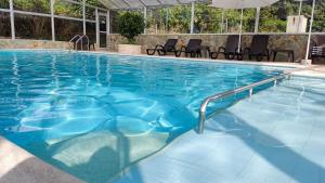 una piscina con agua azul, sillas y sombrilla en HOTEL PANORAMA SOL, en Chachagüí