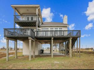 a house on wooden posts with a balcony at Beachfront Envy in Galveston