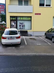 dos autos estacionados en un estacionamiento frente a un edificio en Latic, en Liezen