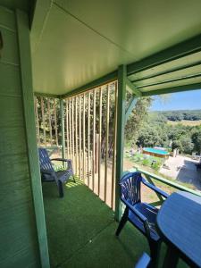 eine abgeschirmte Veranda mit 2 blauen Stühlen und einem Tisch in der Unterkunft Chalet in Petreto-Bicchisano