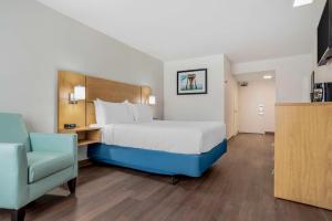- une chambre avec un grand lit et une chaise bleue dans l'établissement Chateau Beachfront Resort - BW Signature Collection, à Panama City Beach