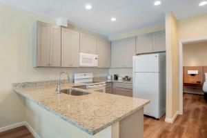 a kitchen with white cabinets and a white refrigerator at Chateau Beachfront Resort - BW Signature Collection in Panama City Beach